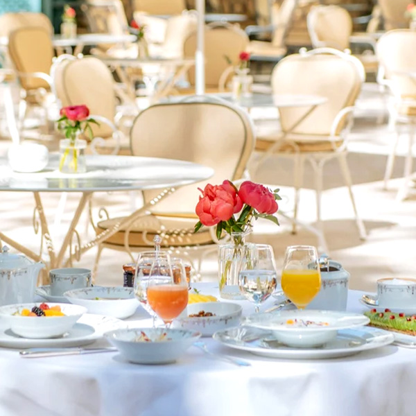 Petit-déjeuner raffiné en terrasse au Ritz Paris – Jus frais, café, viennoiseries et fruits servis sur une table élégante