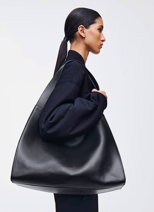 Sac à main noir en cuir signé COS, format oversize, idéal pour un look minimaliste et chic.