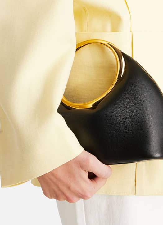 Sac Jacquemus en cuir noir avec anse dorée circulaire, accessoire luxueux et élégant.