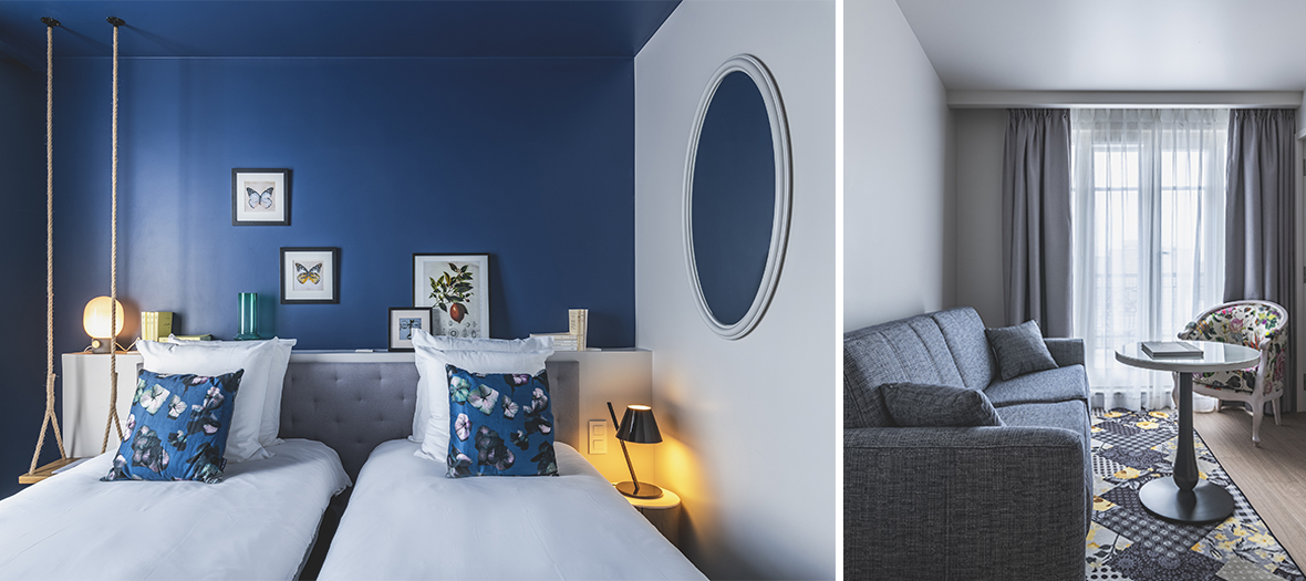 Hôtel Belleval Paris : Chambre au style contemporain avec mur bleu nuit et décoration minimaliste. Salon élégant avec canapé gris et ambiance feutrée.