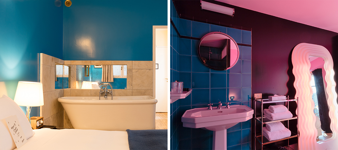 Hôtel Grand Amour Paris : Chambre au style rétro avec baignoire sur pied, murs bleu profond et ambiance romantique. Salle de bain rose et bleue avec miroir lumineux et design audacieux.